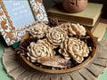 Wooden bowl with decorative flowers and pinecones on a textured surface