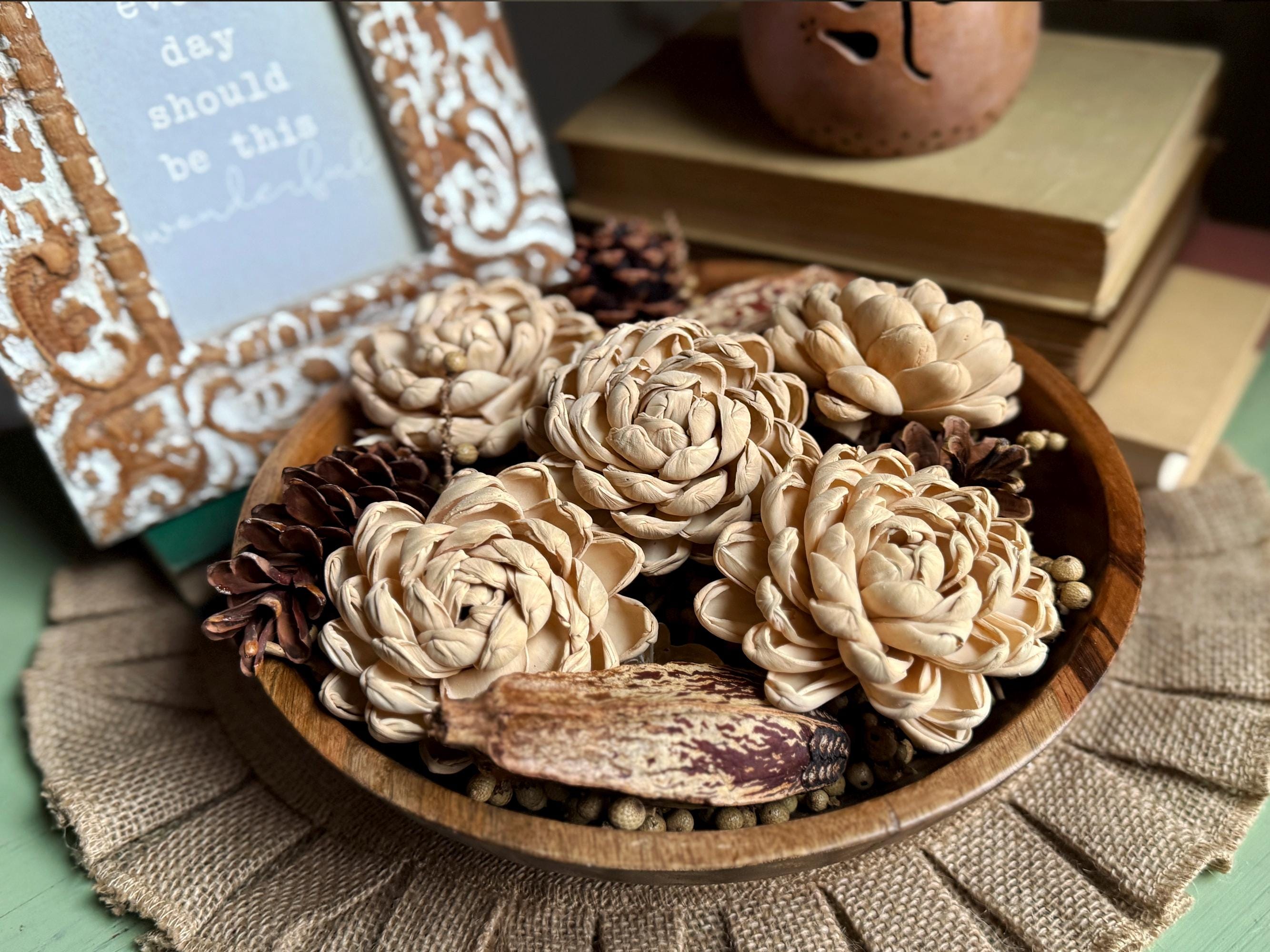 Wooden bowl with decorative flowers and pinecones on a textured surface