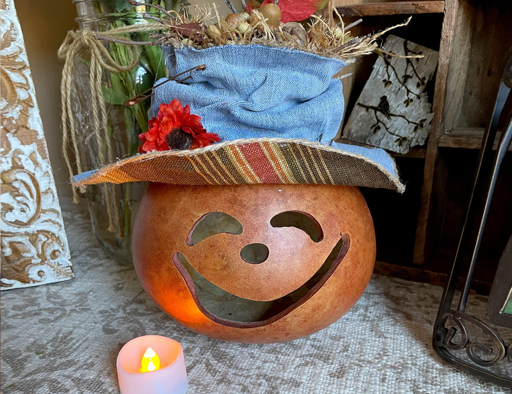 Decorative lantern with a face and a blue cloth on top, lit by a small candle.