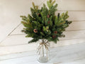 Bouquet of Fraser fur greenery in a glass jar with a white wooden background