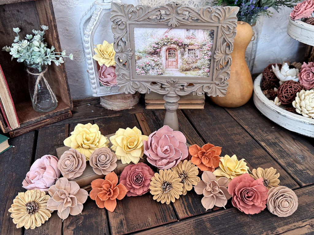 Decorative wood flowers arranged on a wooden surface with a framed picture in the background.
