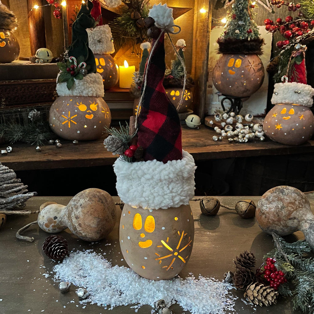 Decorative setup with lit pumpkins, a gnome figure, and festive decorations on a wooden surface.