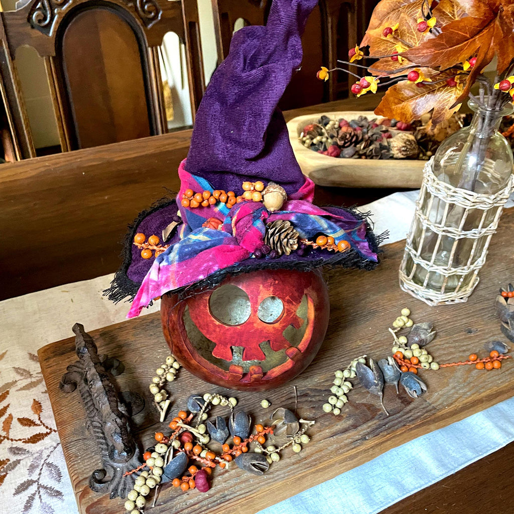 Decorative Halloween pumpkin with a colorful witch hat on a wooden table.