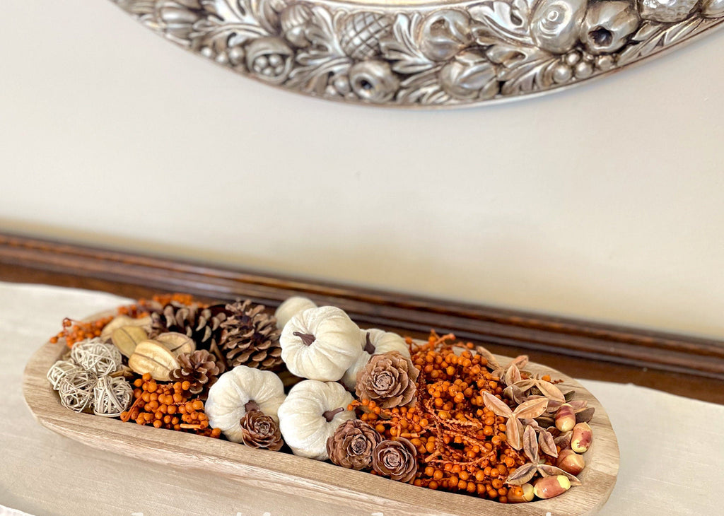 Decorative tray with autumn-themed items including pumpkins, pinecones, and berries on a white surface.