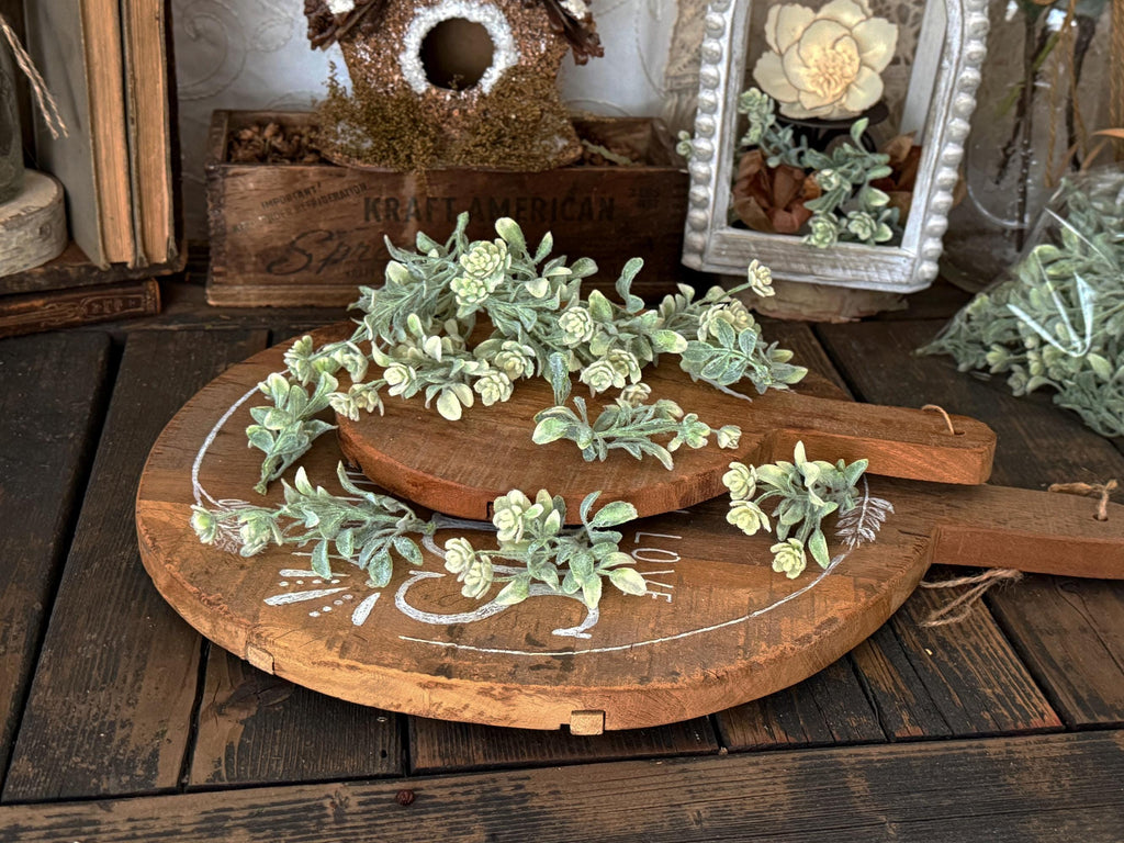 Decorative wooden board with greenery on a rustic wooden surface