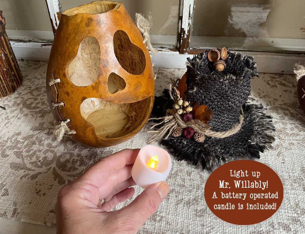 Decorative owl with a battery-operated candle included on a textured surface.