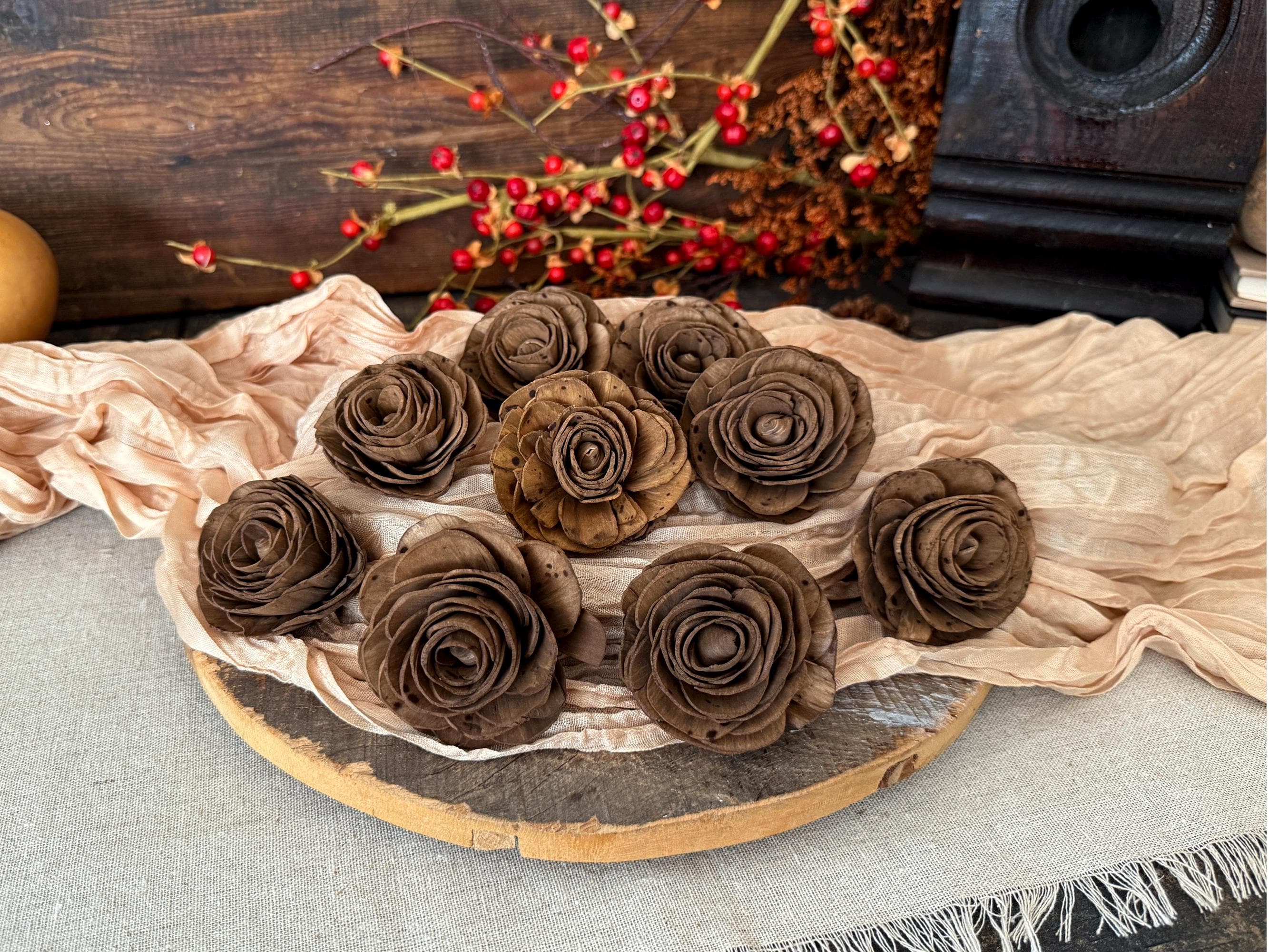 Decorative arrangement of brown pine cones shaped like flowers on a wooden board with a beige cloth underneath.