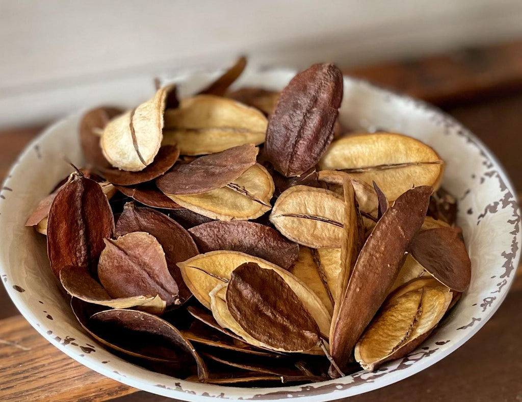 Dried brown and beige leaves in a white bowl on a wooden surface