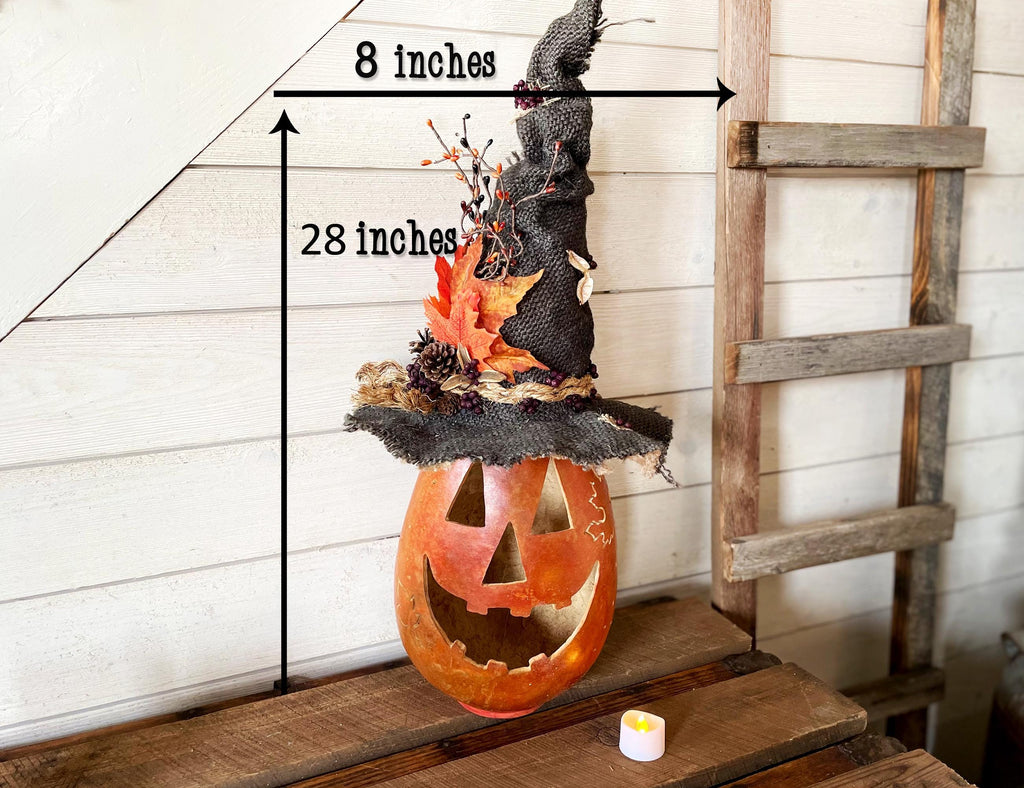 Halloween-themed decoration with a jack-o'-lantern and witch hat on a wooden surface.