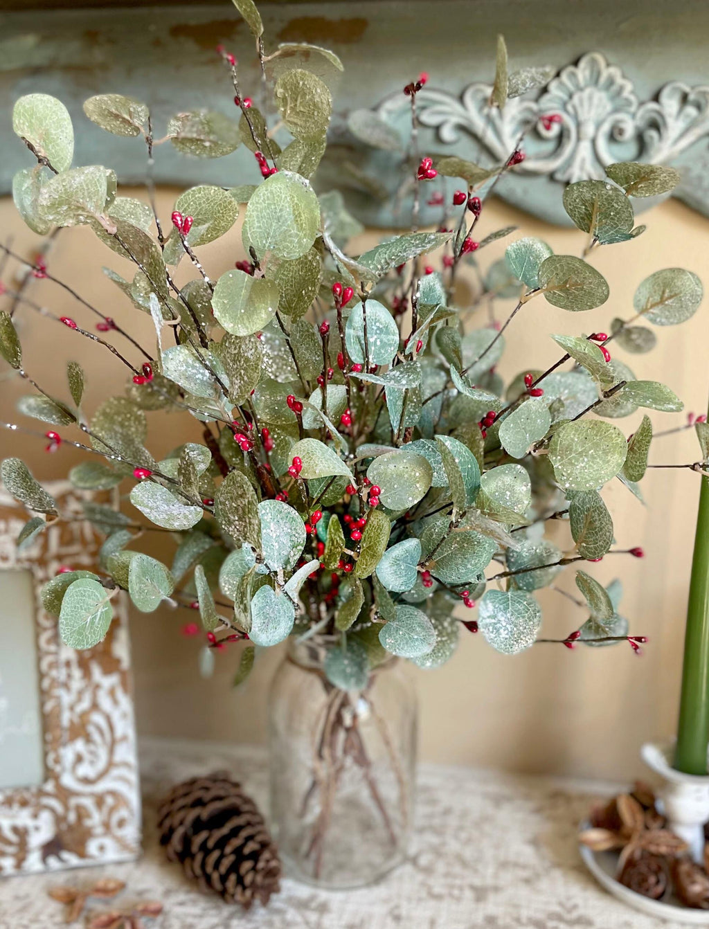 Decorative Christmas bouquet with red berries in a vase on a textured surface.