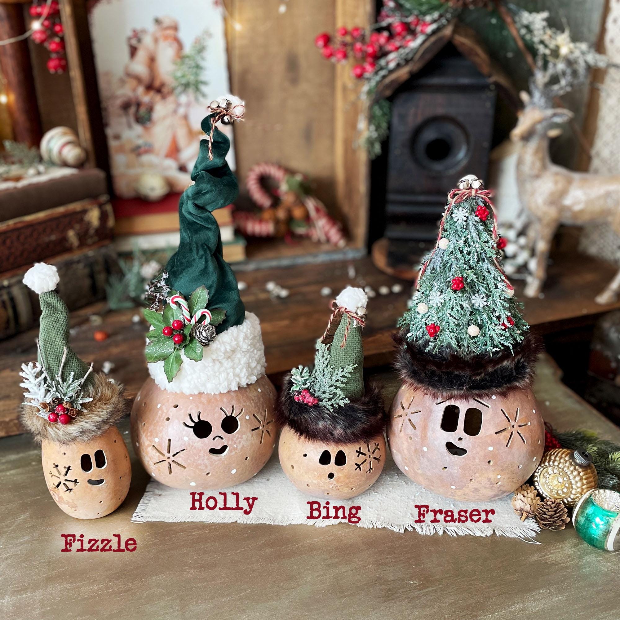 Decorative gourd ornaments with faces and Christmas-themed decorations on a rustic background.