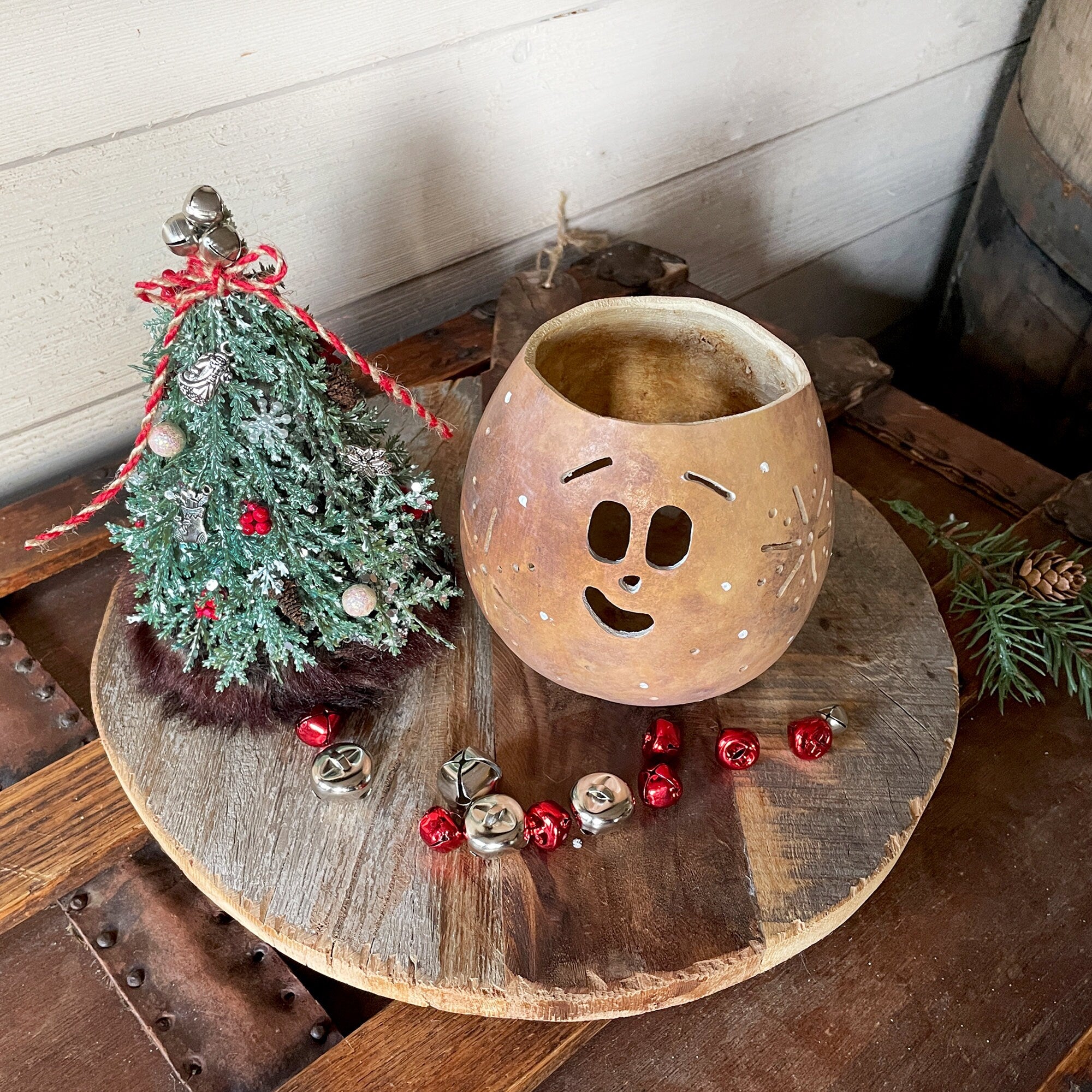 Decorative lantern with face design on a wooden surface with Christmas decorations.