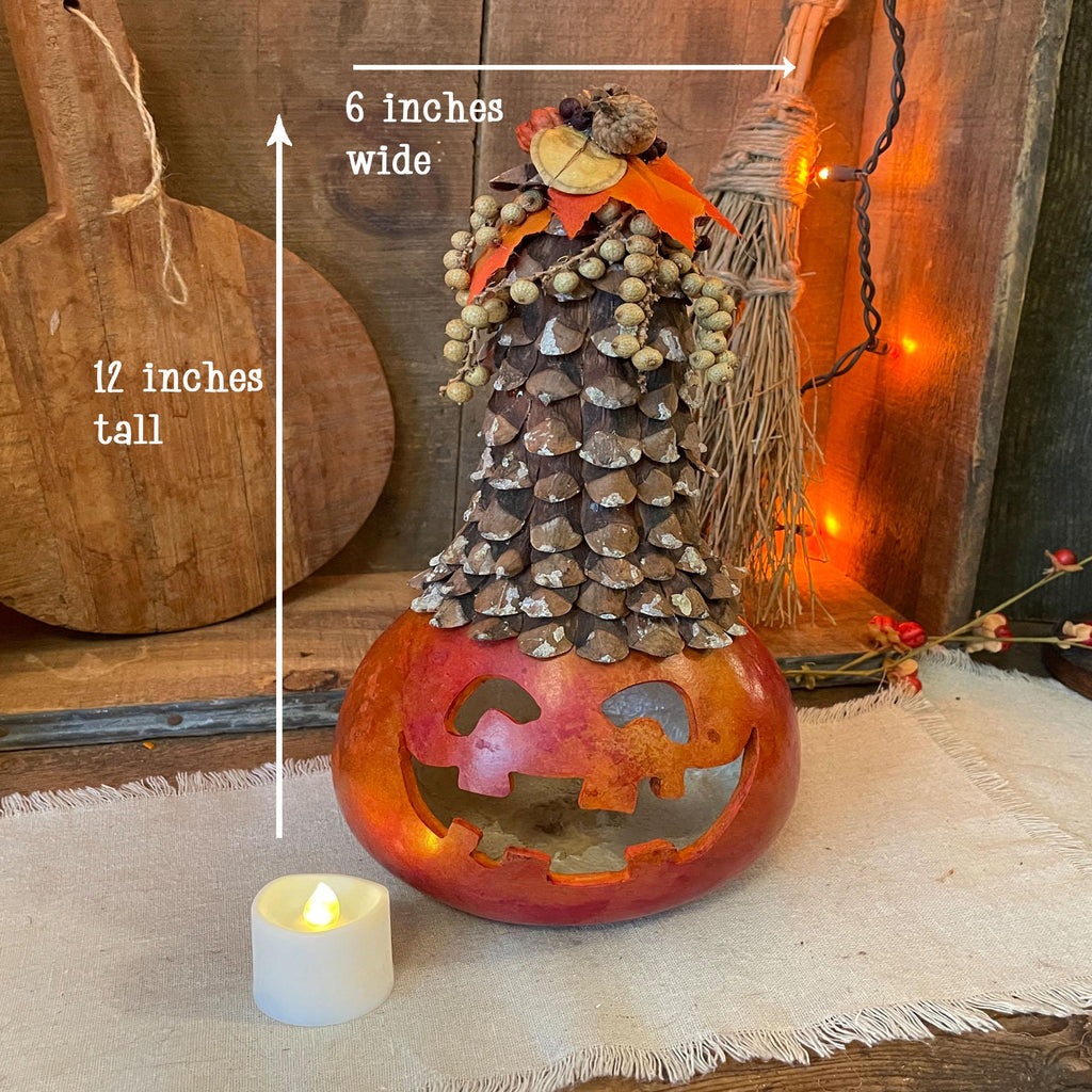 Decorative Halloween pumpkin with pinecone top, measurements indicated, on a wooden surface.