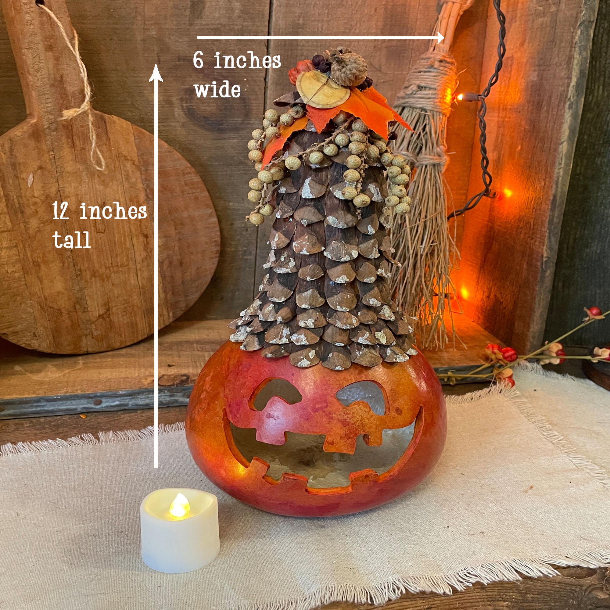 Decorative Halloween pumpkin with pinecone top, measurements indicated, on a wooden surface.