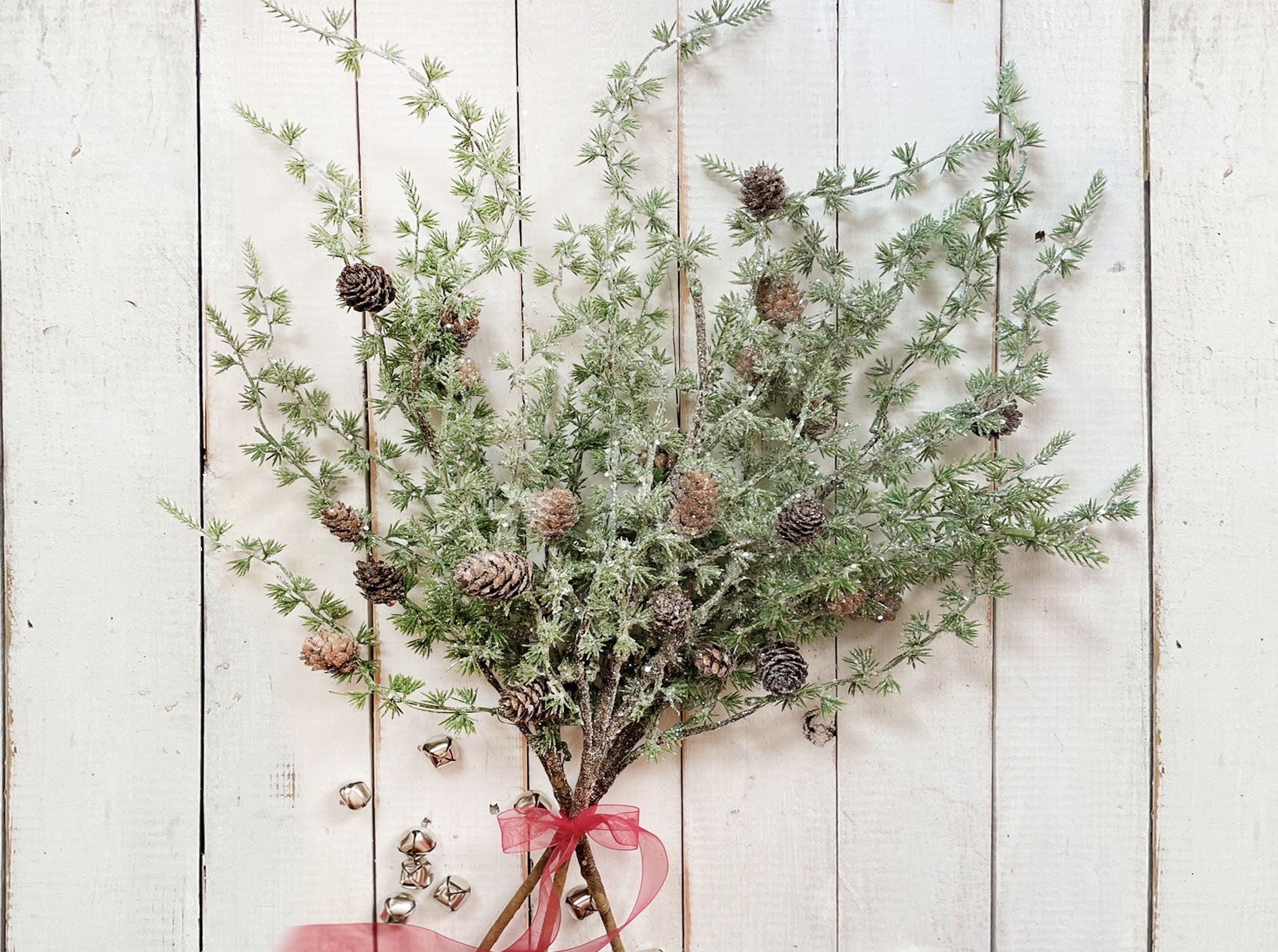 Decorative arrangement of greenery with pinecones on a white wooden background