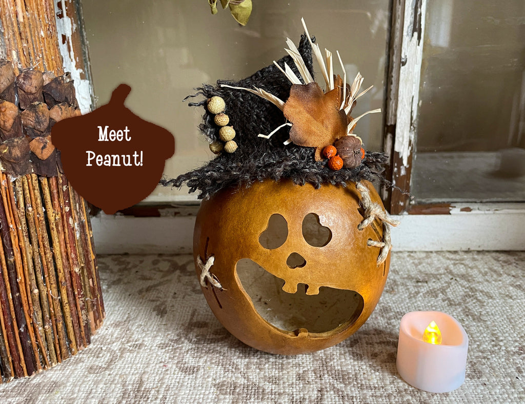 Decorative pumpkin with a face and autumnal decorations on a textured surface with a candle.