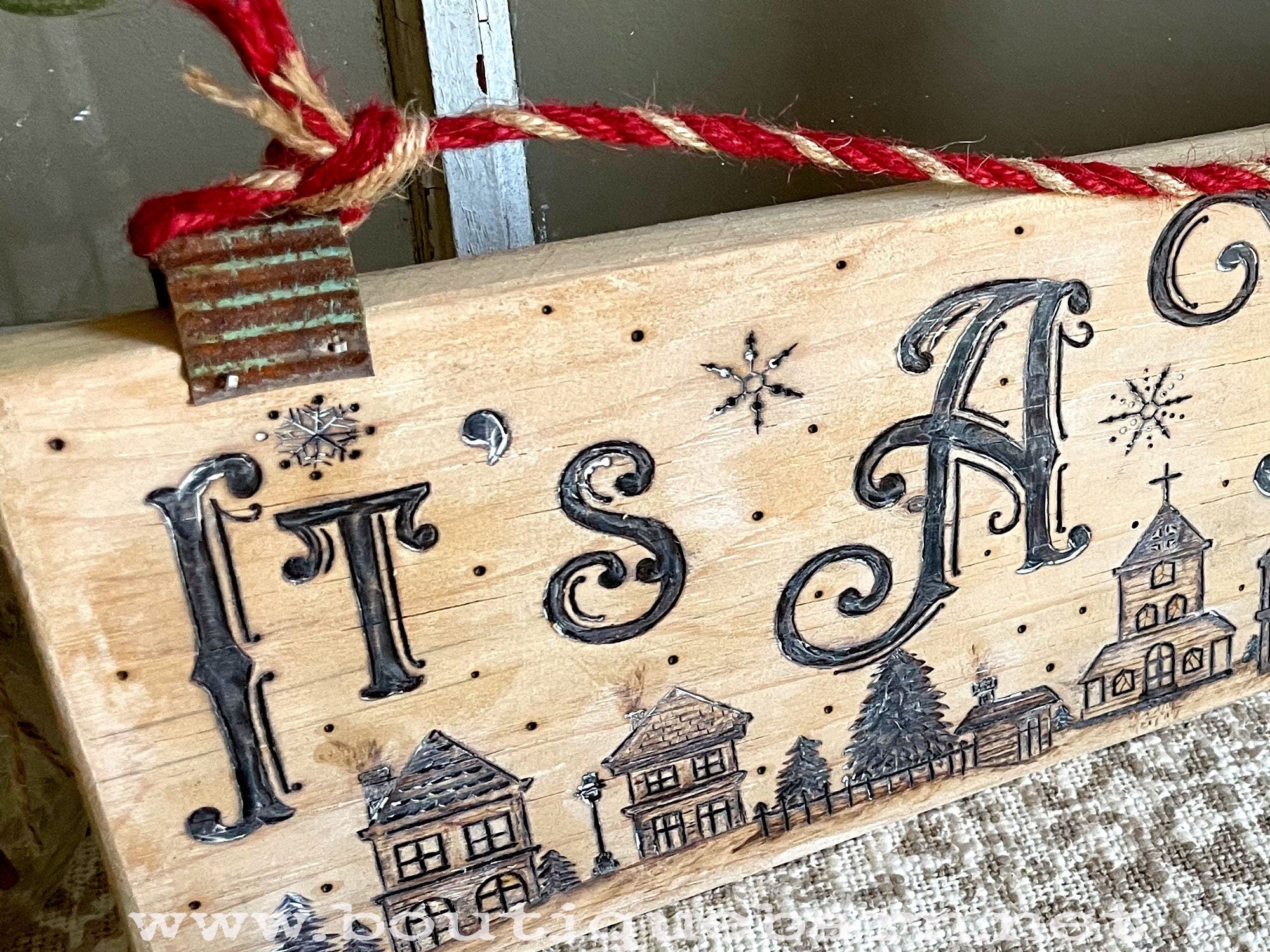 Wooden sign with 'It's A' and decorative elements on a textured surface.