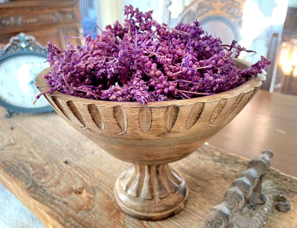 Wooden bowl with purple flowers on a wooden surface