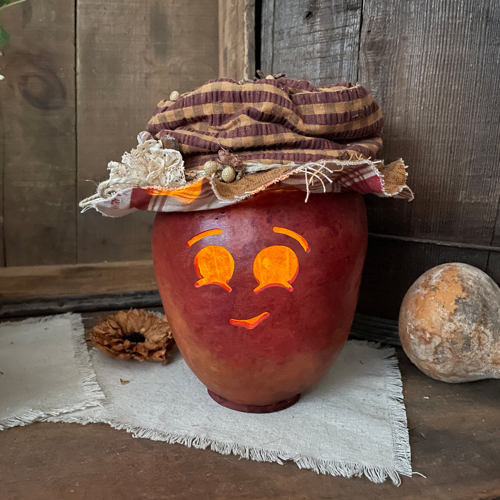 Decorative pumpkin with a face and plaid hat on a rustic wooden surface