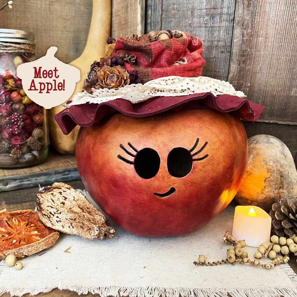 Decorative pumpkin with a face, wearing a red hat, on a rustic background with candles and pinecones.