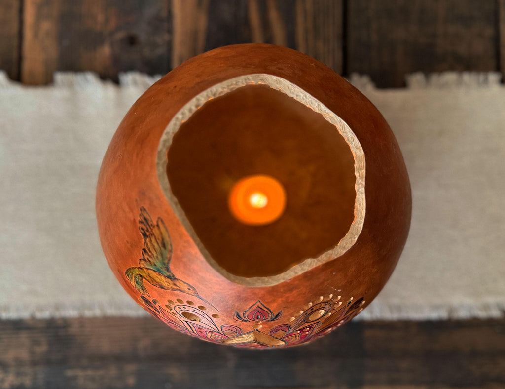 Decorative gourd with a candle inside on a wooden surface
