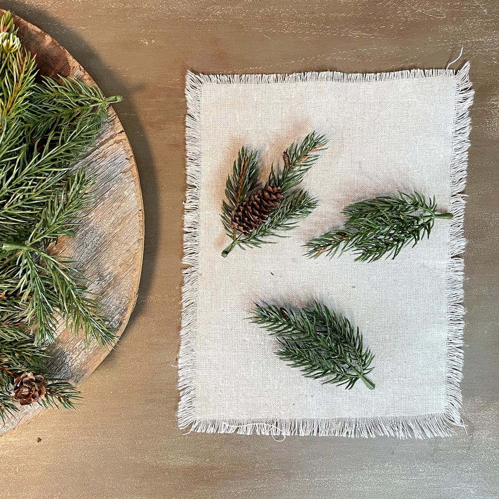 White napkin with greenery and pine cones on a wooden surface