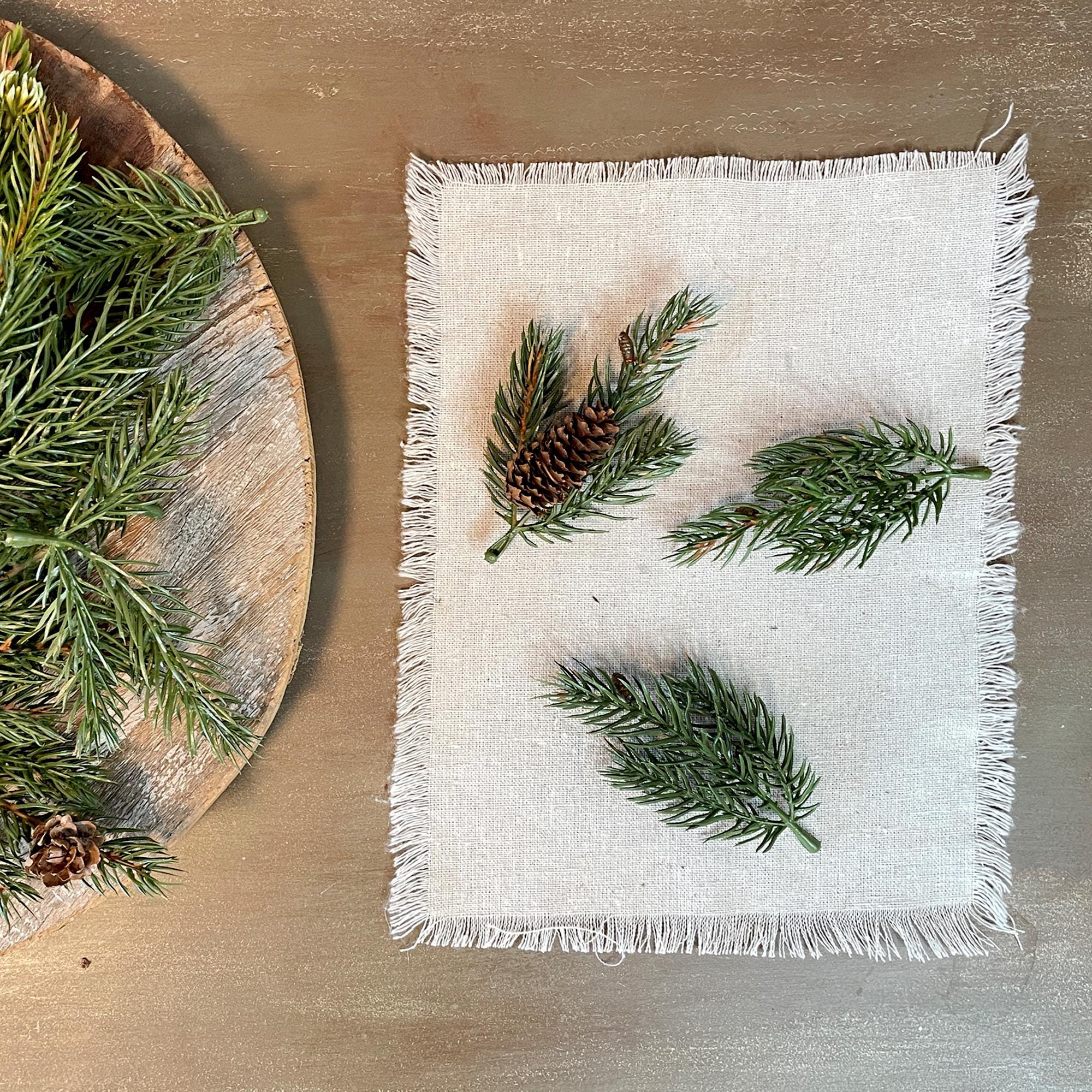 White napkin with greenery and pine cones on a wooden surface