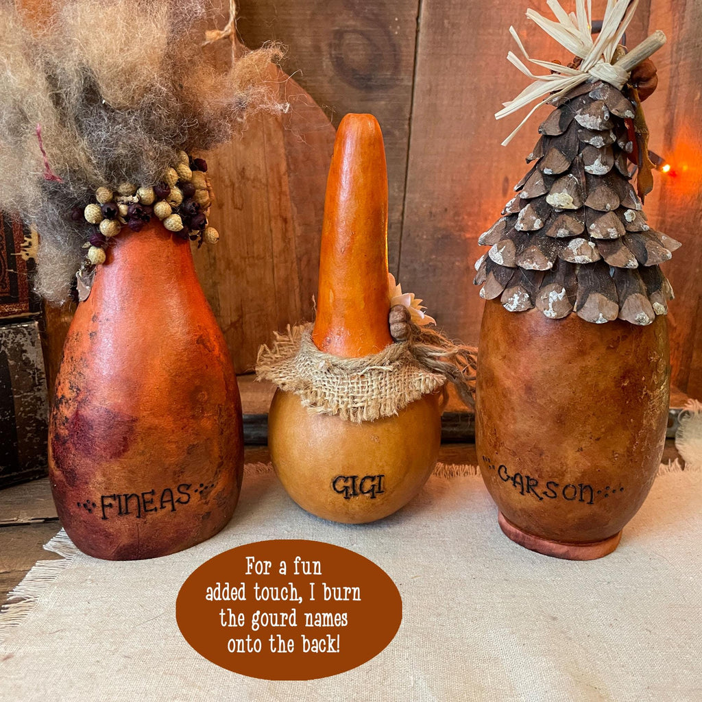 Three gourd decorations with names burned onto them on a wooden surface.