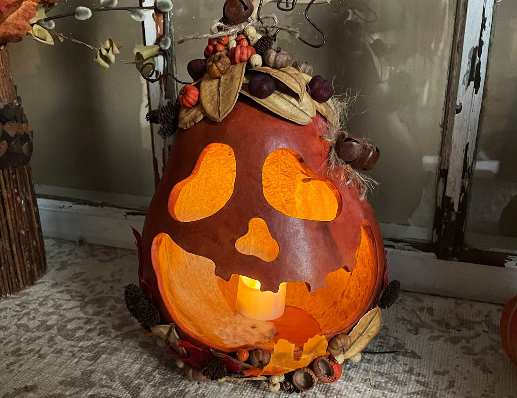Decorative pumpkin with carved face and autumnal elements on a textured surface.