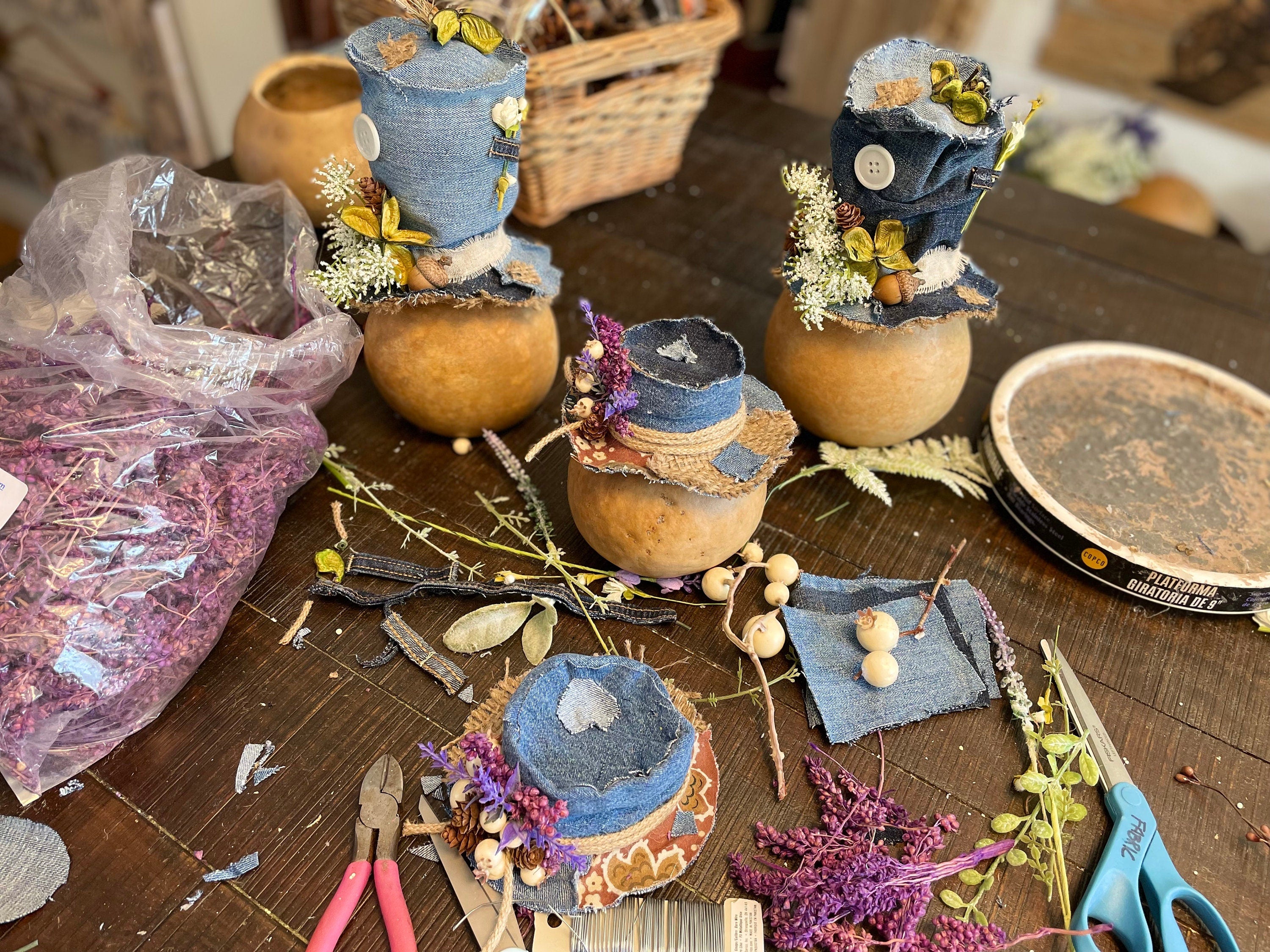 Decorative items made from pumpkins, fabric, and flowers on a table with tools and materials.