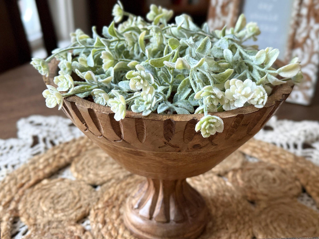 Decorative wooden bowl with artificial greenery on a textured surface