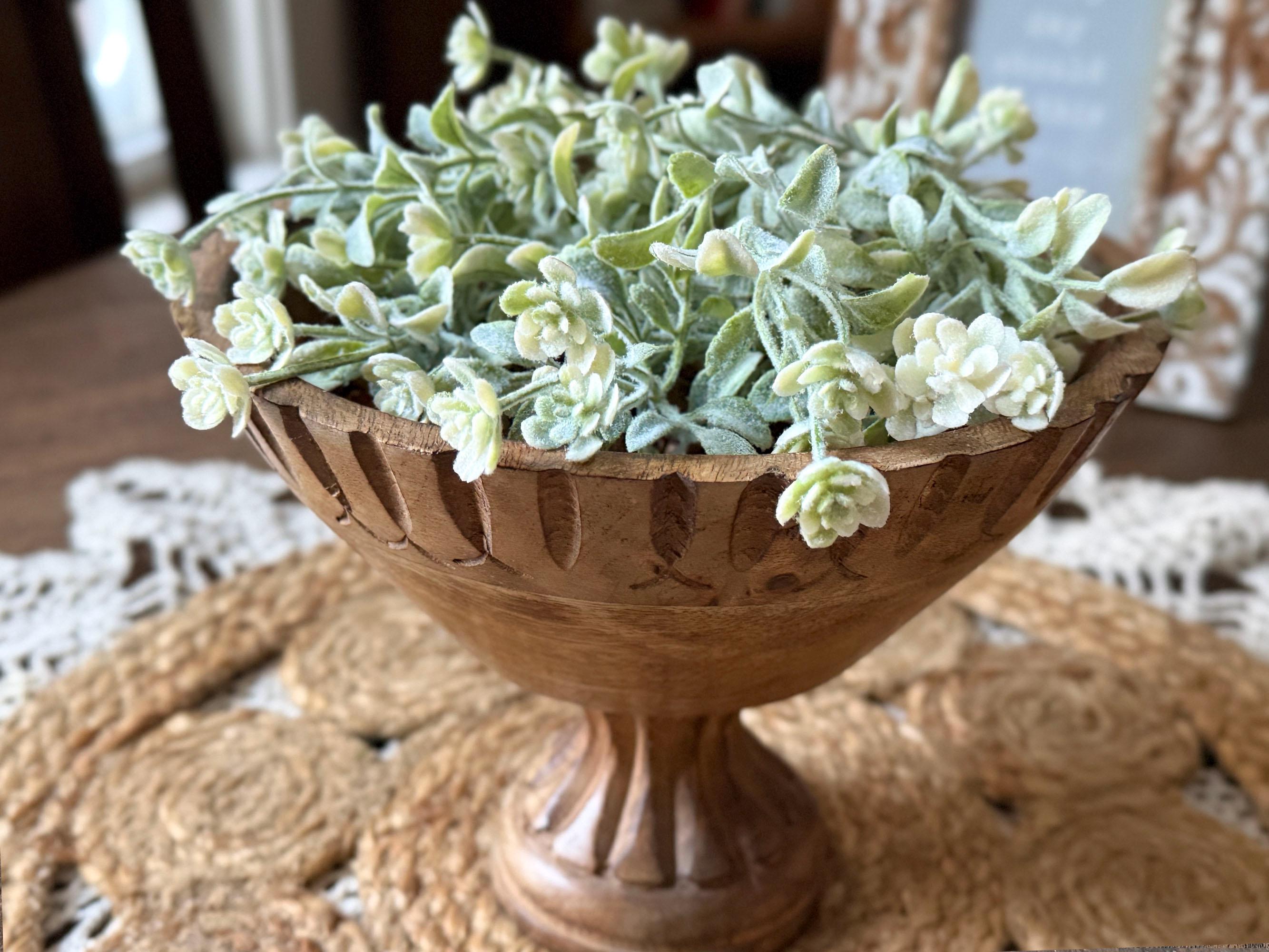Decorative wooden bowl with artificial greenery on a textured surface