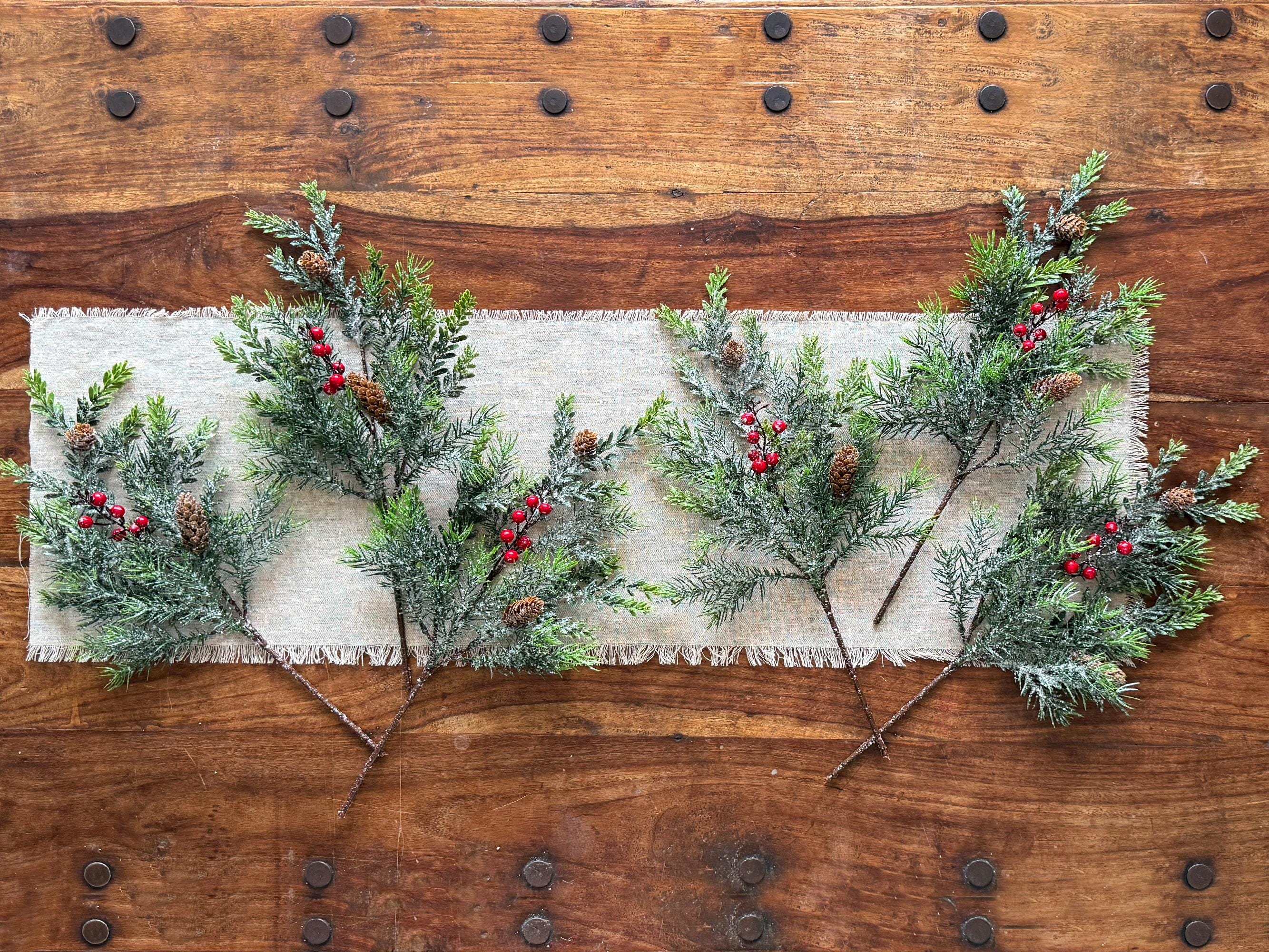 Decorative greenery with red berries on a white fabric runner against a wooden background