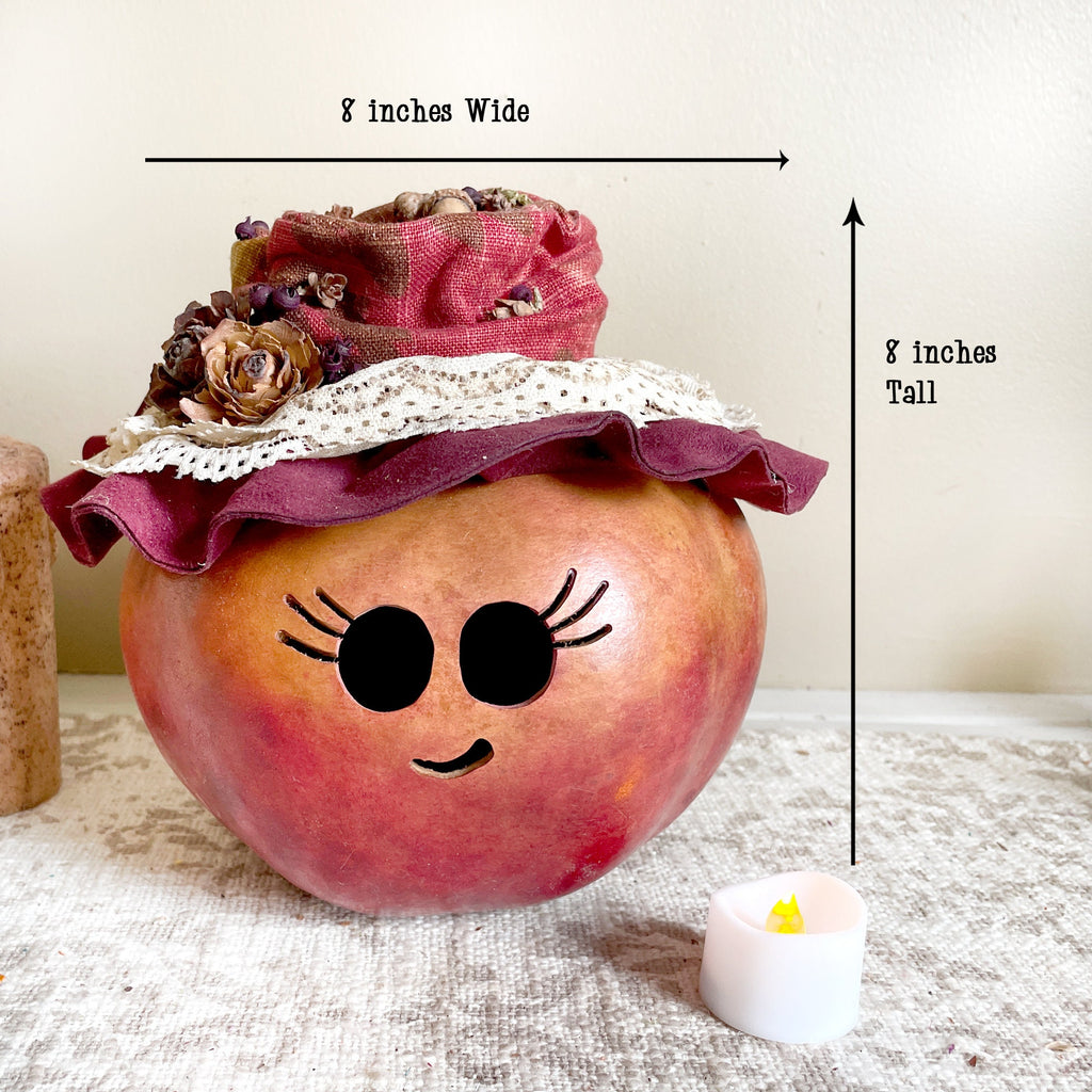 Decorative apple with a pink hat and face features, labeled for width and height.