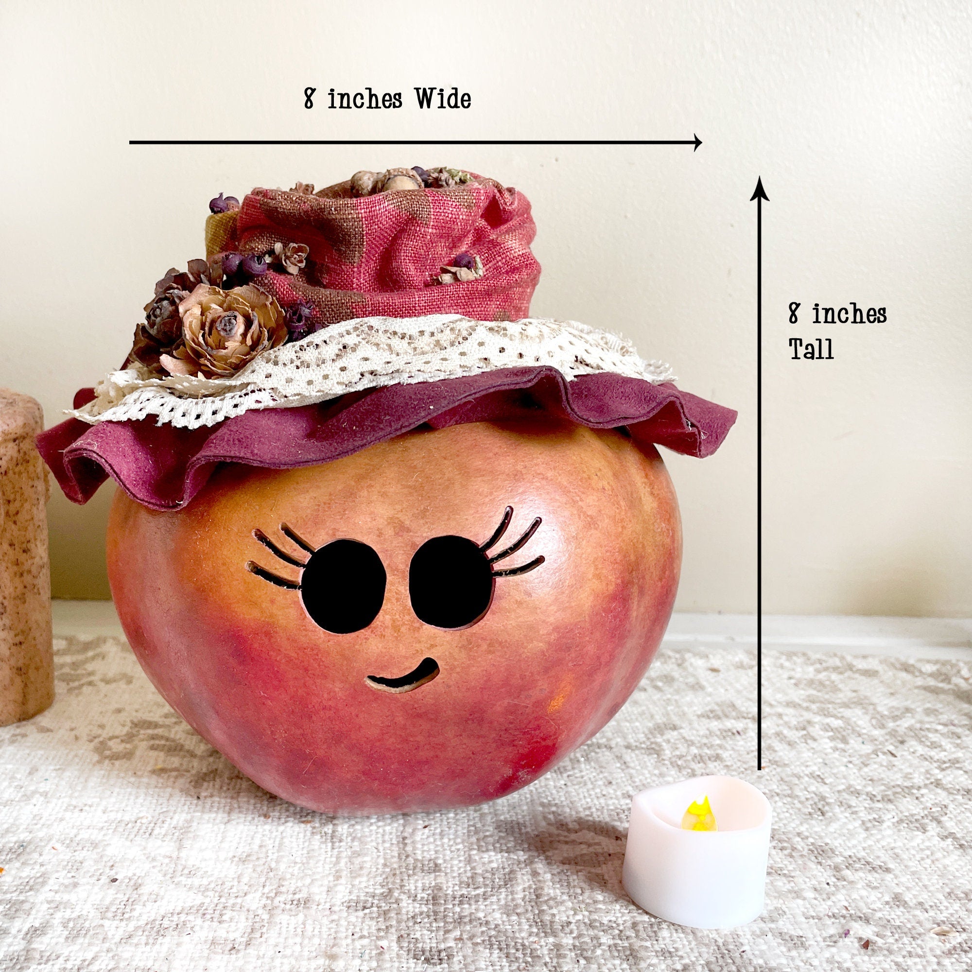 Decorative apple with a pink hat and face features, labeled for width and height.