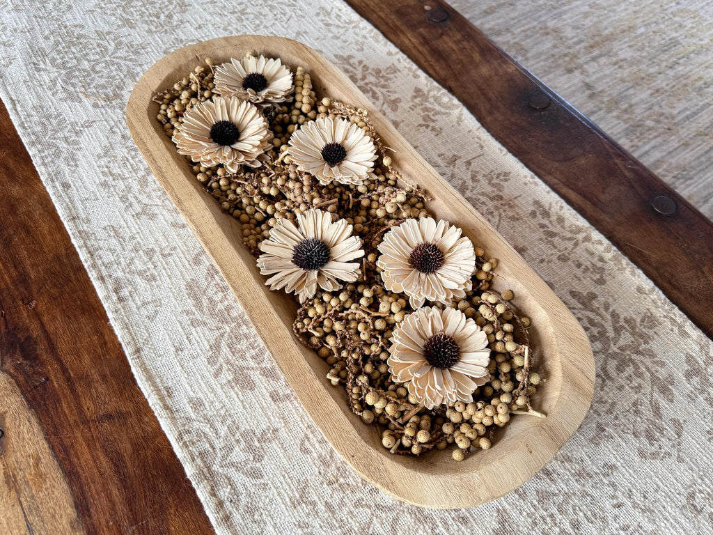Decorative wooden tray with dried flowers on a textured surface
