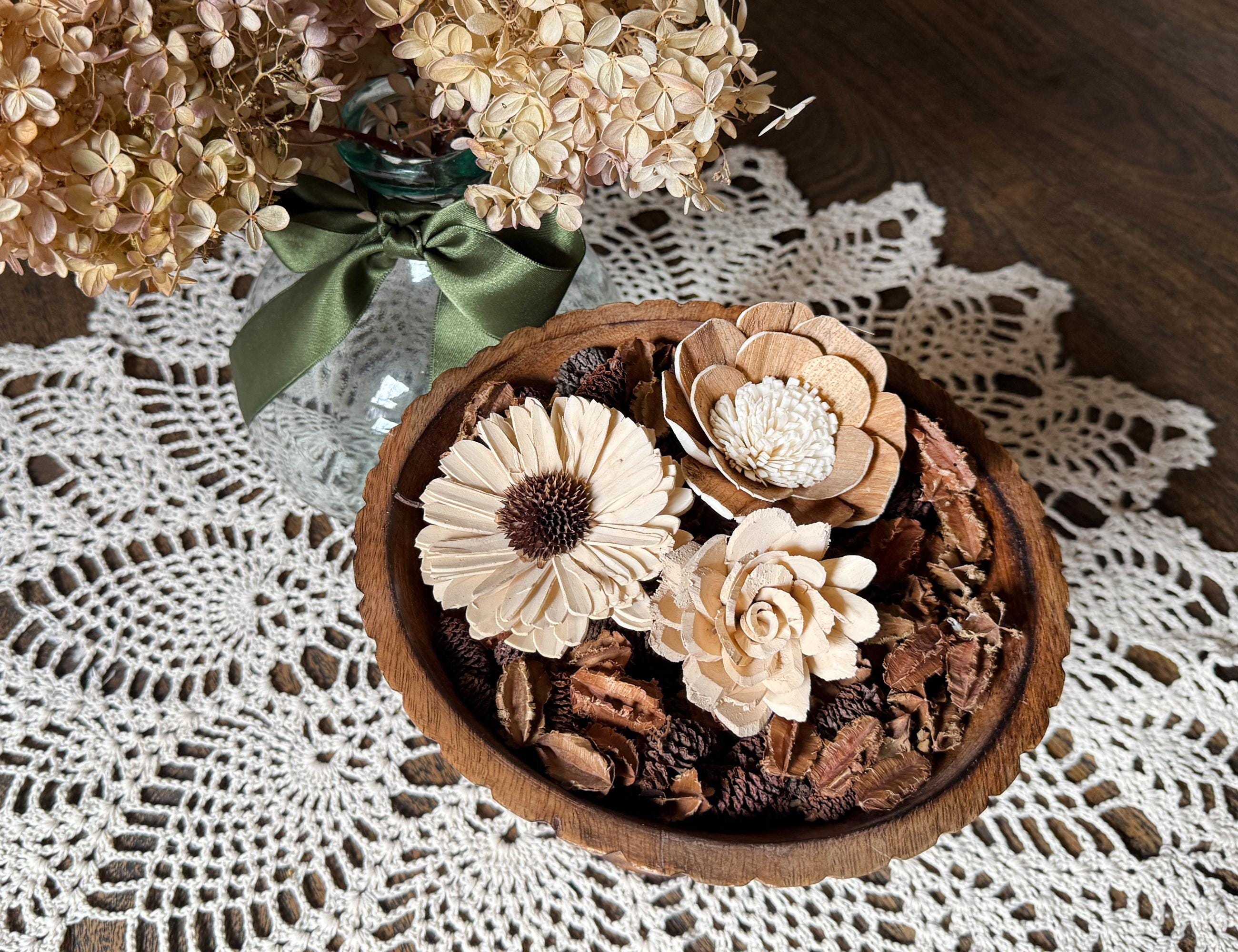 Wooden bowl with decorative flowers and pinecones on a lace tablecloth
