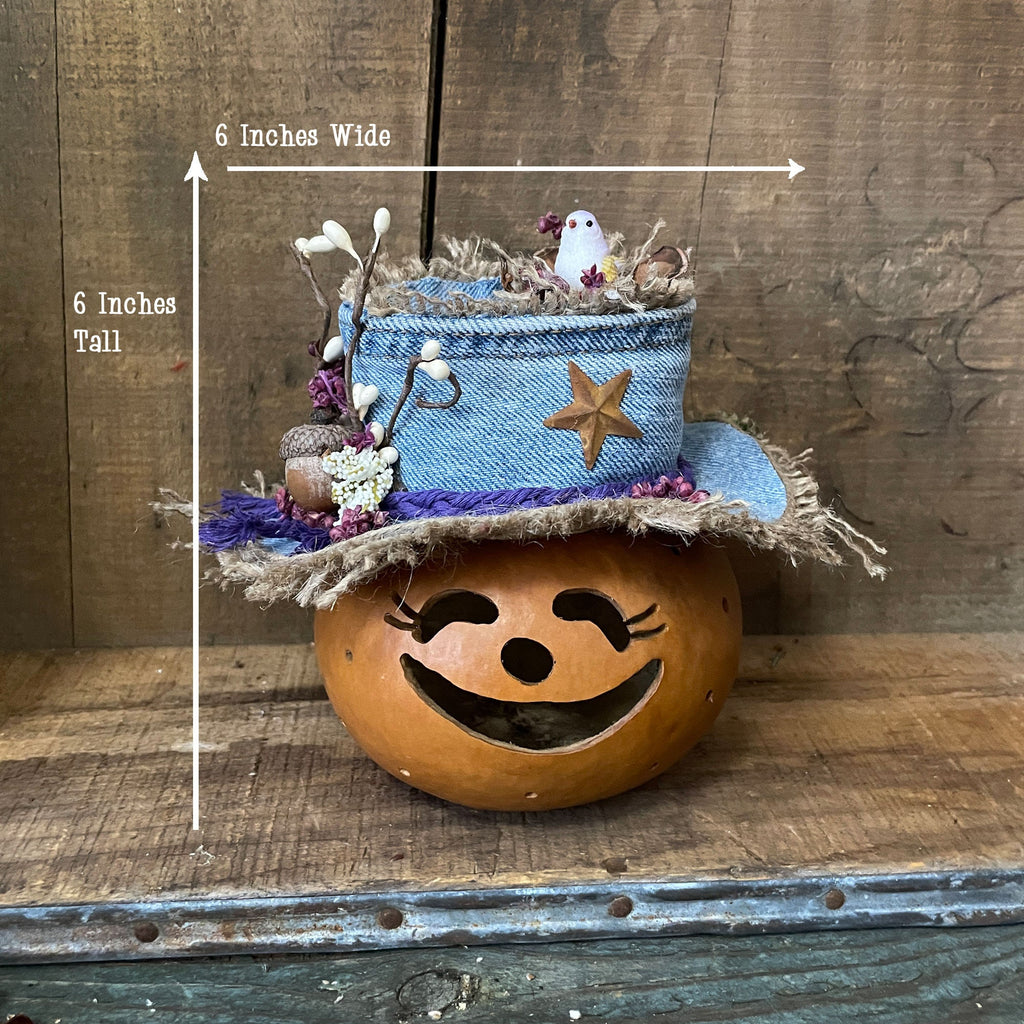 Decorative pumpkin with a blue denim hat on a wooden surface, showing measurements.