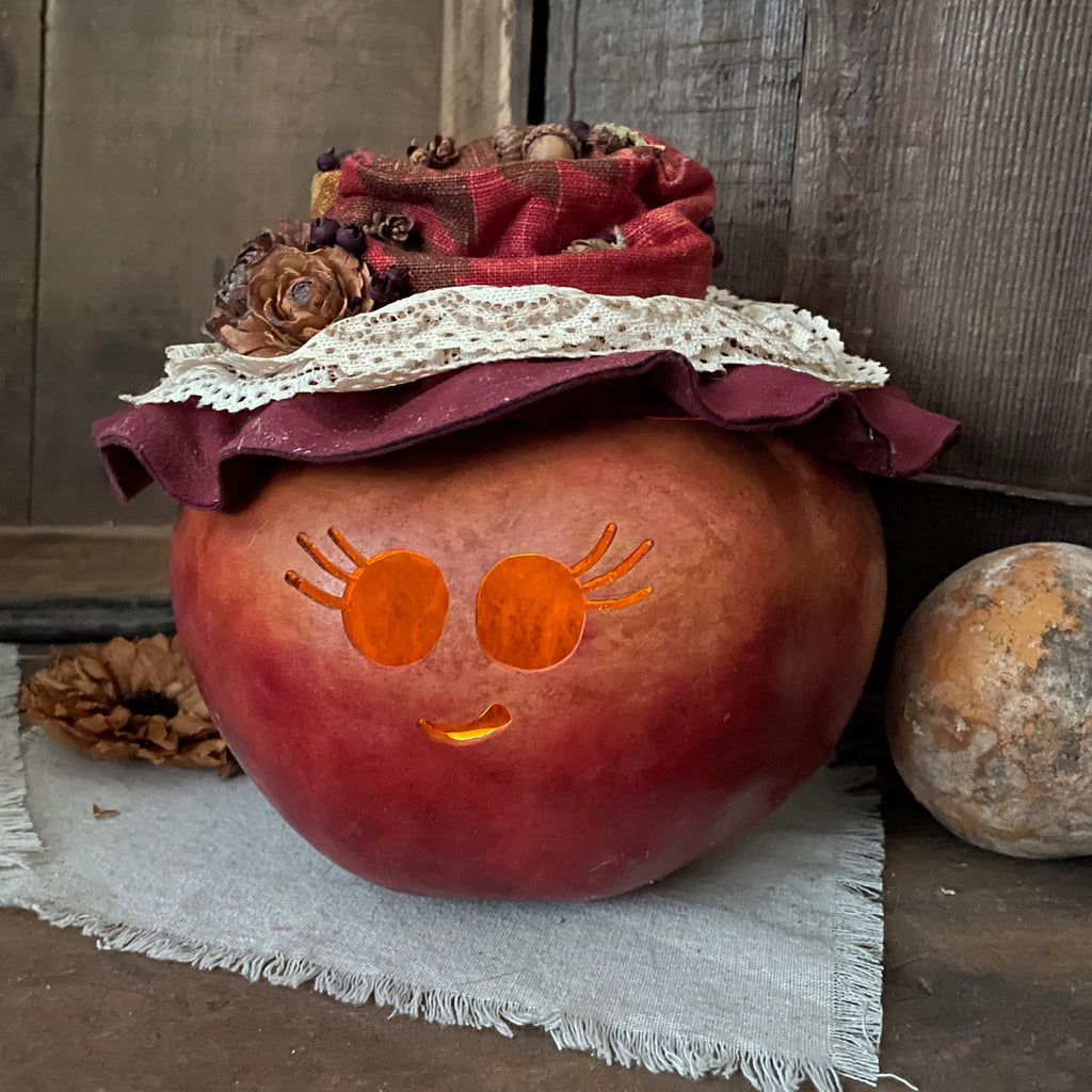 Decorative pumpkin with a face and fabric hat on a rustic wooden background