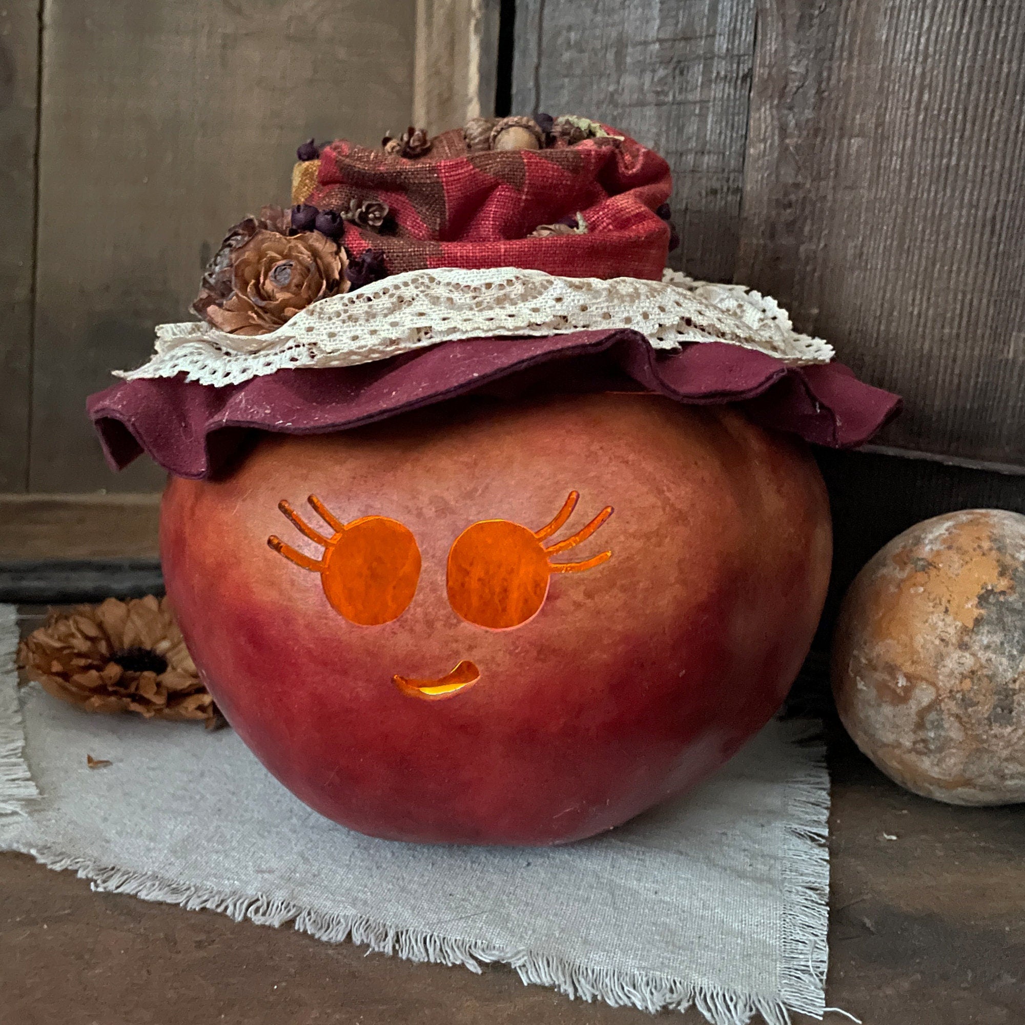 Decorative pumpkin with a face and fabric hat on a rustic wooden background