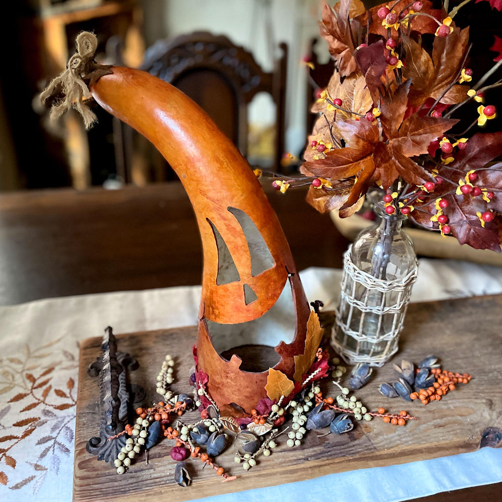 Decorative gourd with leaf and berry arrangement on a wooden surface