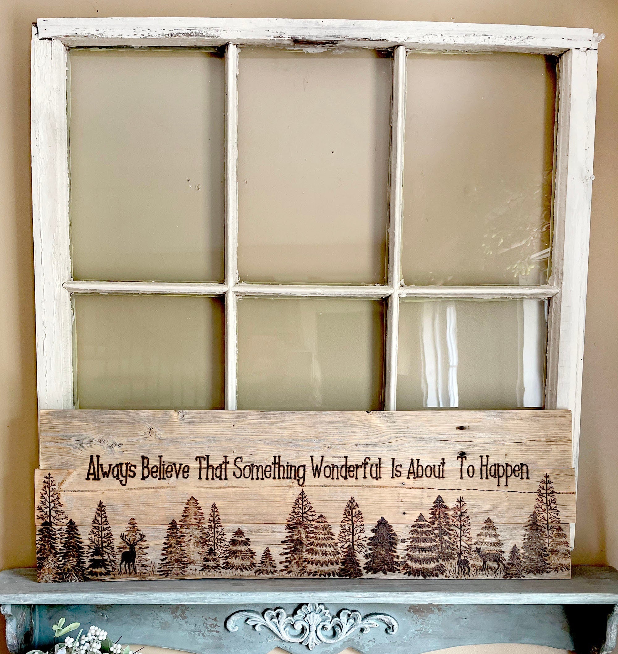Wooden sign with nature design and text inside a repurposed window frame on a shelf.