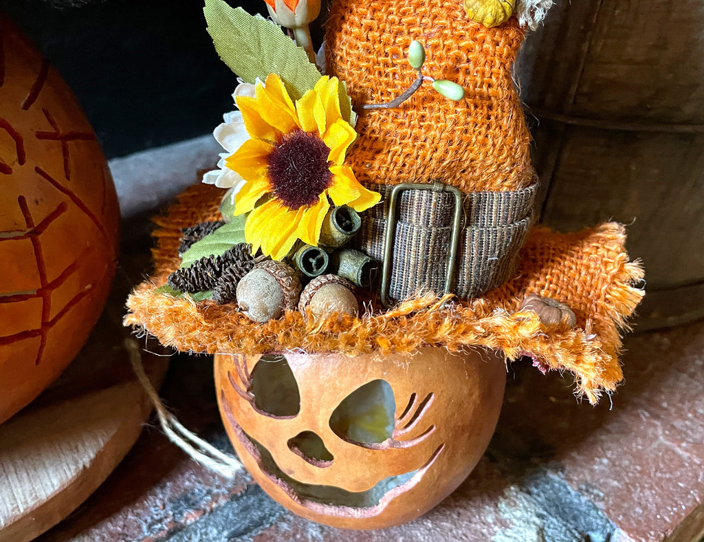 Decorative pumpkin with a sunflower and straw hat on a rustic surface