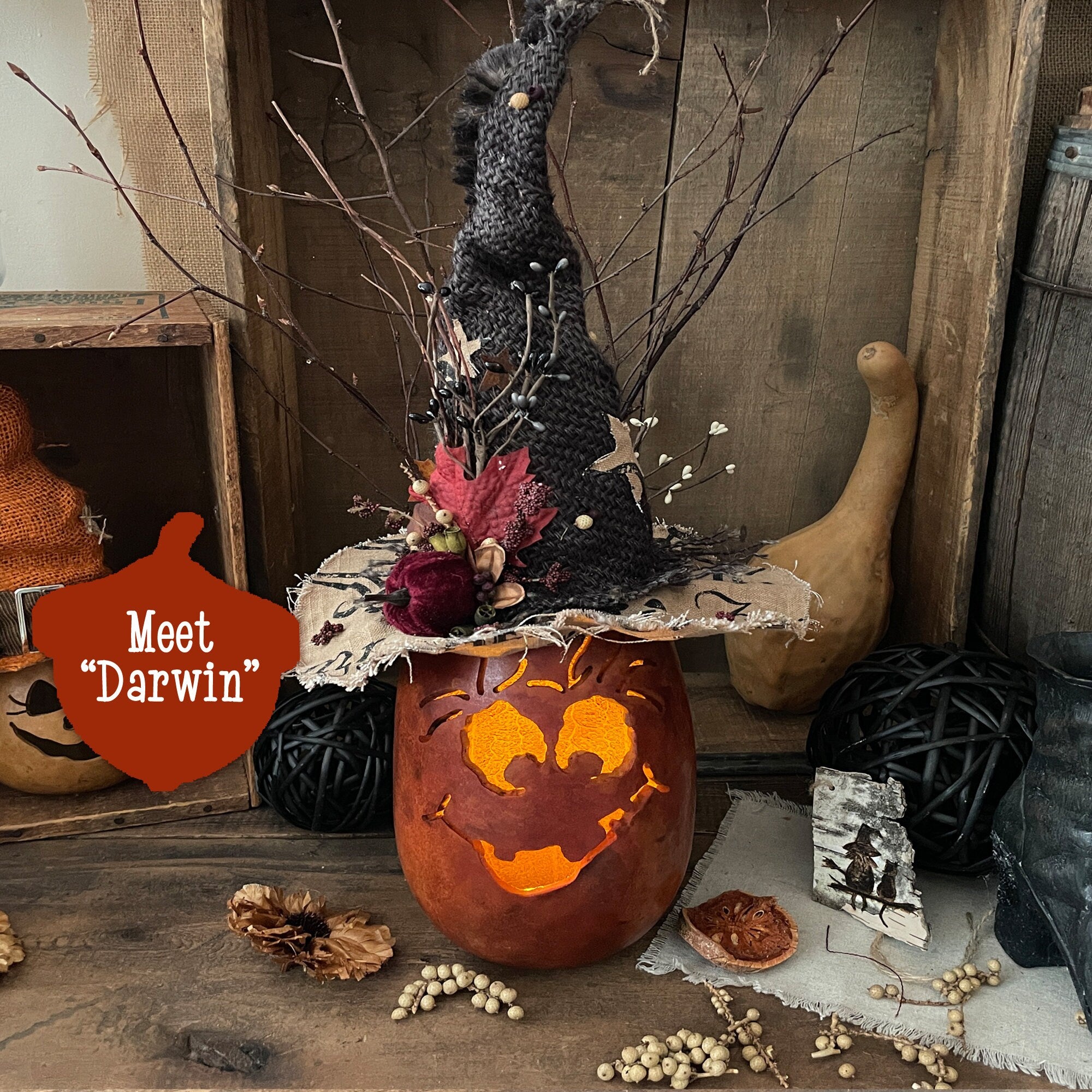 Halloween-themed display with a carved pumpkin, decorative figure, and gourds on a rustic background.