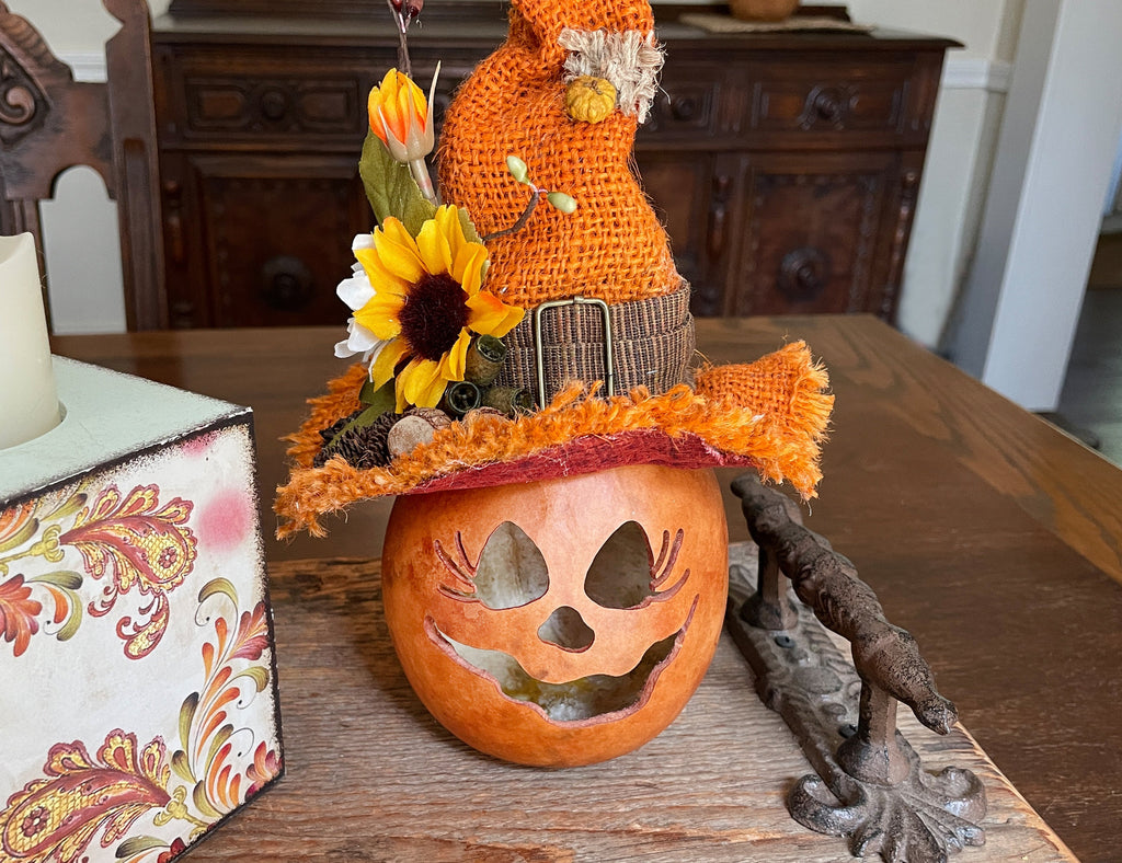 Decorative pumpkin with a gnome and sunflower on a wooden surface