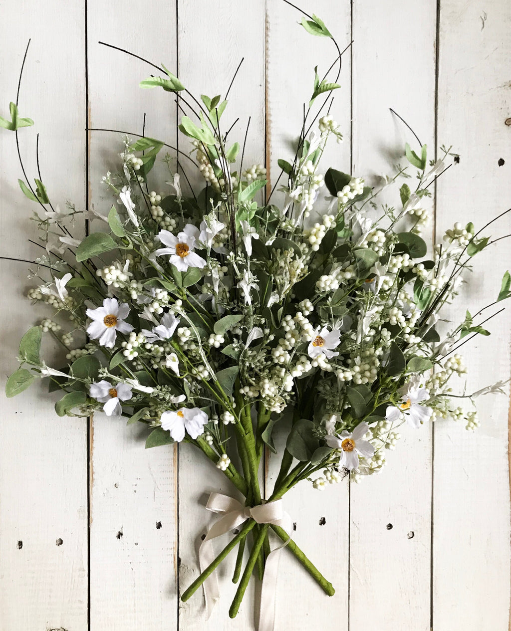 Bouquet of white flowers with green leaves on a wooden background
