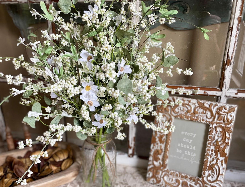 Bouquet of white flowers in a vase with a decorative frame in the background