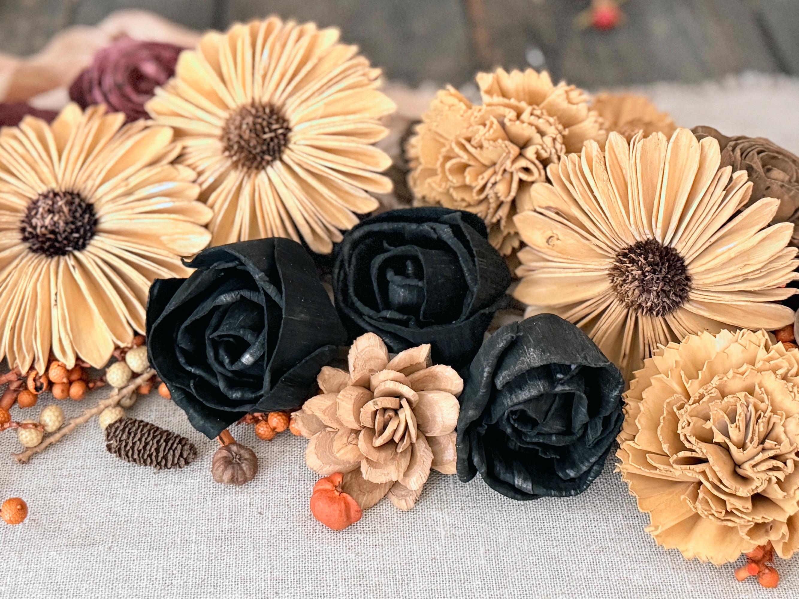 Arrangement of black roses and beige flowers on a textured surface