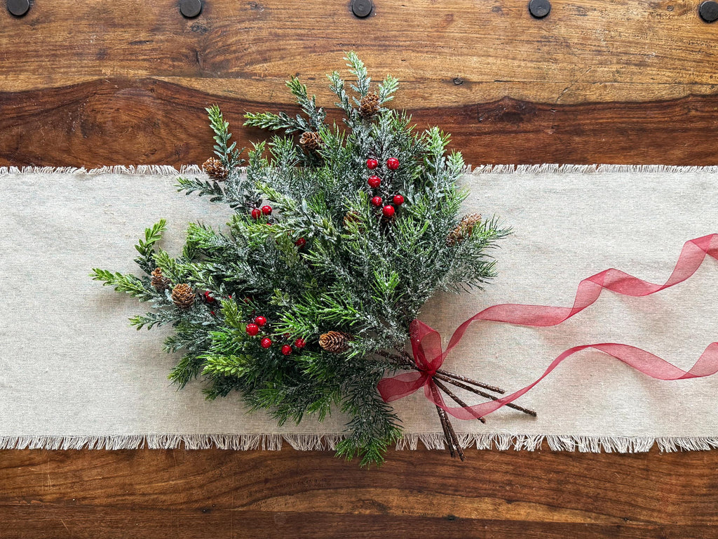 Decorative Christmas wreath with red berries on a wooden table with a white runner.