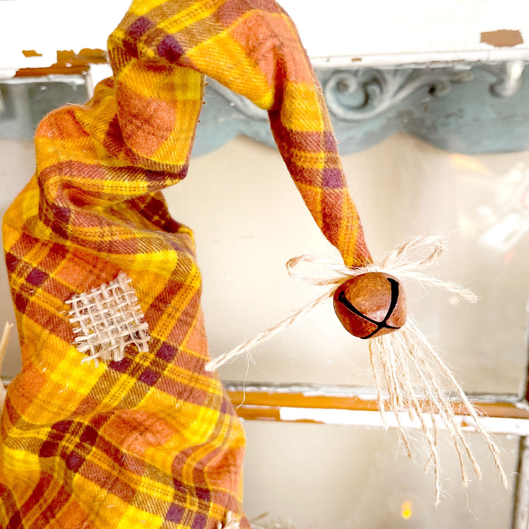 Decorative cat-shaped candle with plaid pattern and bell on a white background